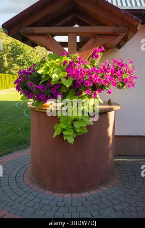 Un grand pot de fleurs violet se trouve sur une passerelle en briques. Le pot est rempli d'une variété de fleurs, y compris violettes et vertes. Les fleurs sont arran Banque D'Images