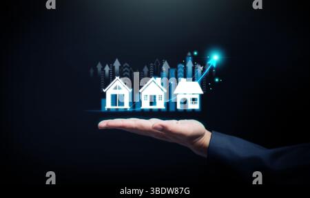 Concept de croissance immobilière. La main tient les icônes de maison et la courbe ascendante, symbolisant l'investissement immobilier, l'expansion du marché et le développement immobilier. Banque D'Images