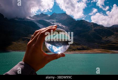 Lac suisse limpide et montagnes majestueuses reflétées dans une boule de lentilles, créant un mélange magique de nature, de lumière et de perspective unique. Banque D'Images