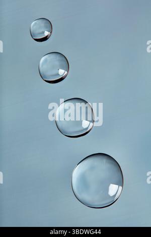 Gouttelettes d'eau disposées en diagonale sur une surface lisse bleu clair. Banque D'Images