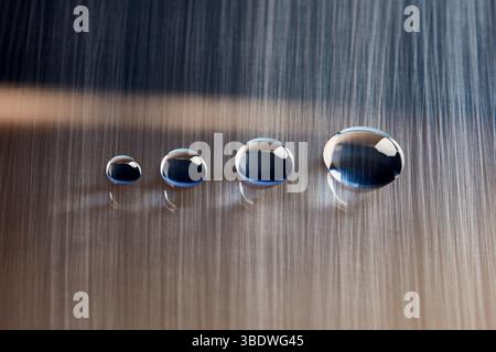 Gouttelettes d'eau disposées horizontalement sur une surface lisse gris clair. Banque D'Images