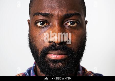 Gros plan portrait de l'homme noir ennuyé qui regarde la caméra. Banque D'Images