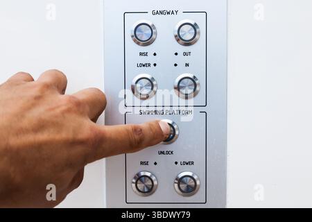 Main de l'homme poussant le bouton de commande d'une plate-forme pour plonger à partir d'un yacht. Banque D'Images