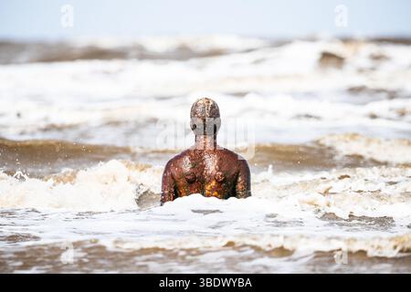 Gros plan d'une statue d'Iron Man sur la plage de Crosby face à la mer d'Irlande à marée haute. Banque D'Images
