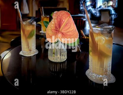 3 verres de cocktail avec rhum et tranche de citron et une énorme fleur rose dans un vase Banque D'Images