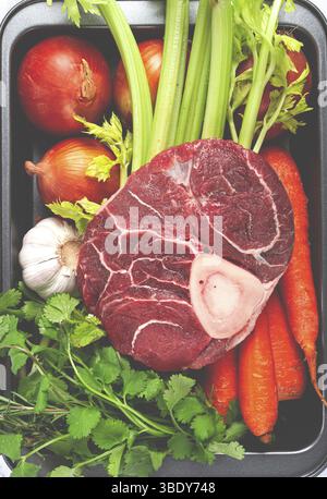 Knuckle sur l'os, viande crue pour ossobuco, avec des légumes, dans un panier, ingrédients pour la cuisson ossobuco, vue de dessus, pas de gens Banque D'Images