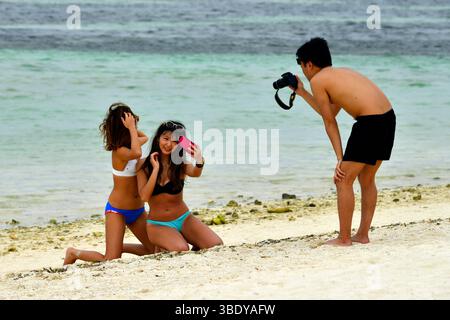 Photographe prenant des photos de jeunes femmes sur la plage de Kondoi sur l'île de Taketomi dans la préfecture d'Okinawa, Japon, Asie. Banque D'Images
