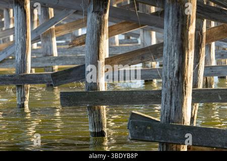 Un charmant pont piétonnier en bois s'étend sur la rivière, ses planches altérées offrant un chemin rustique à travers la nature. Le flux serein du ri Banque D'Images