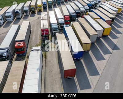 Vue aérienne d'un grand parking de camions à un centre logistique, avec plusieurs semi-camions commerciaux stationnés en rangées organisées. Banque D'Images