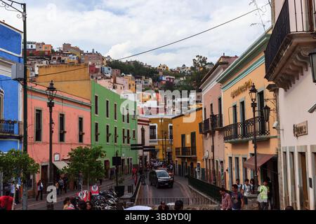 Guanajuato City, Mexique - 30 mai 2016 : les gens marchent et une voiture roule dans une rue bordée de bâtiments colorés dans la ville de Guanajuato. Banque D'Images