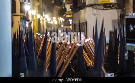 Nazarenos de Gran Poder défilent dans les rues de Séville tenant des bougies, créant une atmosphère solennelle pendant les festivités de la semaine Sainte. Banque D'Images
