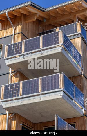 Panneaux solaires sur les balcons d'un nouveau bâtiment revêtu de bois en Suisse Banque D'Images