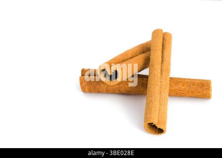 Pose plate de fragments d'écorce de cannelle sur un fond blanc, soulignant leur aspect rustique, leur texture fibreuse et leurs teintes terreuses, adaptées à la food-re Banque D'Images