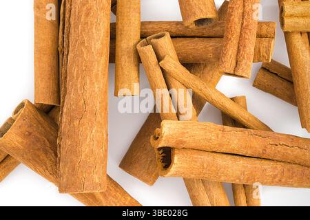 Plusieurs fragments d'écorce de cannelle frisés affichés sur un fond blanc propre, soulignant leurs formes organiques, leur texture fibreuse et leurs teintes chaudes, perf Banque D'Images