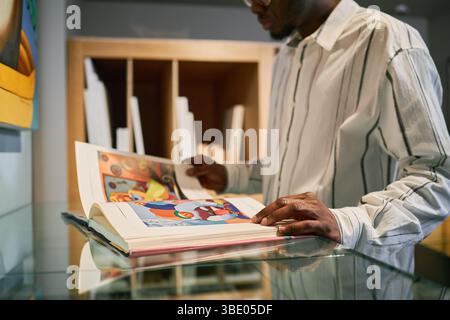 Homme lisant livre illustré dans la librairie moderne Banque D'Images