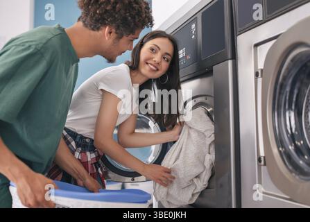 Happy couple linge pliant ensemble à la laverie automatique lave-linge intérieur Banque D'Images