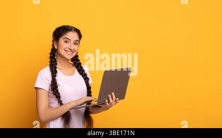 Jeune femme indienne confiante tenant et utilisant un ordinateur portable Banque D'Images