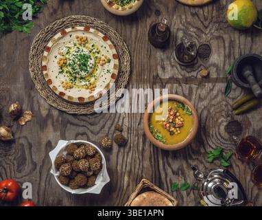 Plateau de petit-déjeuner arabe traditionnel avec falafel, houmous et fèves disposées sur une surface rustique en bois, vue de dessus Banque D'Images