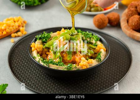 Fèves de Fava avec houmous, surmontées d'huile d'olive – assiette de petit déjeuner arabe traditionnelle. Banque D'Images