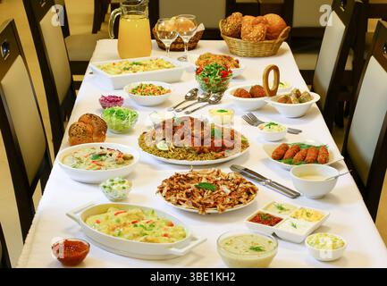Table élégante avec riz jaune et poulet grillé entier, présentation de la cuisine arabe traditionnelle Banque D'Images