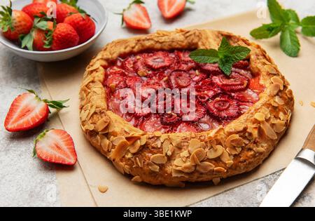 Galette de fraises fraîchement cuite décorée de flocons d'amandes et de feuilles de menthe, incarnant la bonté maison Banque D'Images
