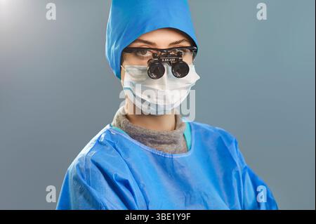 Médecin chirurgien portant un uniforme médical bleu et des loupes binoculaires regardant la caméra à l'hôpital Banque D'Images