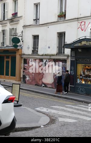 Couple se promène devant expressif Kissing couple mural sur la rue de Paris Banque D'Images