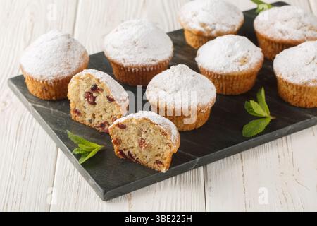 Stollen muffins allemands traditionnels de Noël avec du sucre en poudre, des raisins secs, des fruits confits en gros plan sur la planche sur la table en bois. Horizontal Banque D'Images