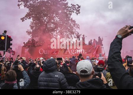 Des foules de fans de Liverpool avec des bombes fumigènes rouges et des téléphones portables sur Queens Drive saluent le bus du Liverpool FC pendant le défilé de la premier League. Banque D'Images