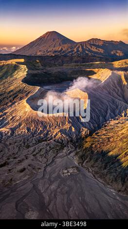 Indonésie, île de Java, province de Java oriental, massif du Tengger, parc national bromo-Tengger-Semeru, volcan fumant bromo (2329 m), ancien volcan Batok (premier plan) et volcan Semeru (3676 m, arrière-plan) à l'aube, vue aérienne panoramique (vue aérienne) Banque D'Images