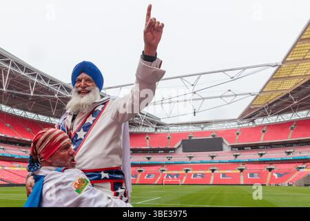 Evel Knievel 50e anniversaire, stade de Wembley, Londres, Royaume-Uni. 27 mai 2025. Pour marquer le 50e anniversaire de la tentative de saut en bus du légendaire cycliste Evel Knievel's Wembley Stadium (26 mai 1975), plus de 50 supporters, tous habillés comme le héros casse-tête, posent avec un bus londonien original des années 1970. M. Singh avait voyagé du Canada et son costume avait été fait spécialement pour l'occasion. Crédit : Amanda Rose/Alamy Live News Banque D'Images