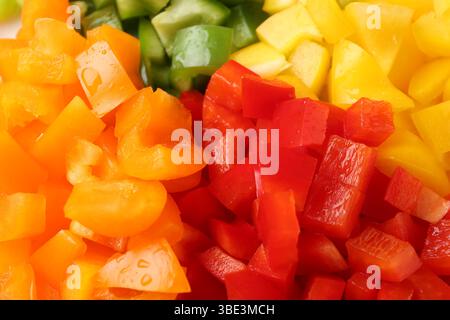 Morceaux de poivrons frais colorés avec des gouttes d'eau comme fond, gros plan Banque D'Images