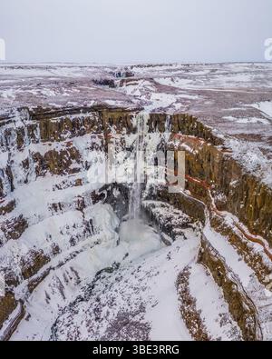 Vue aérienne de la cascade enneigée de Hengifoss dans l'est de l'Islande en hiver. Banque D'Images