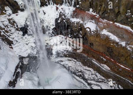 Vue aérienne rapprochée de la cascade gelée de Hengifoss dans l'est de l'Islande. Banque D'Images