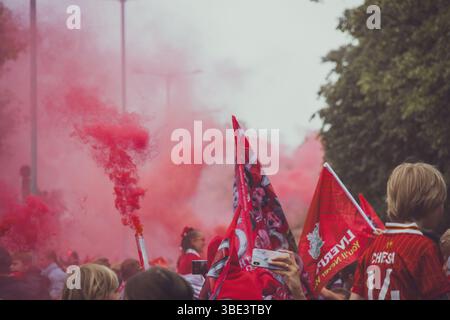 Des foules de fans de Liverpool avec des bombes fumigènes rouges et des drapeaux sur Queens Drive attendant de saluer le bus du Liverpool FC pendant le défilé de la premier League. Banque D'Images