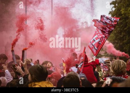 Des foules de fans de Liverpool avec des bombes fumigènes rouges et des drapeaux sur Queens Drive attendant de saluer le bus du Liverpool FC pendant le défilé de la premier League. Banque D'Images