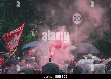 Des foules de fans de Liverpool avec des bombes fumigènes rouges et des drapeaux sur Queens Drive attendant de saluer le bus du Liverpool FC pendant le défilé de la premier League. Banque D'Images