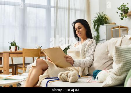 Une jeune et belle femme enceinte se détend à la maison, s'engageant avec ses intérêts créatifs. Banque D'Images