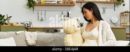 La mère qui attend profite d'un moment tendre avec l'ours en peluche dans son espace de vie élégant et accueillant. Banque D'Images