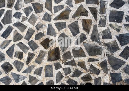 Mur de pierre avec un motif de carreaux noirs et blancs. Le mur est en pierre et a une texture rugueuse. Les tuiles sont disposées de manière à créer un Banque D'Images