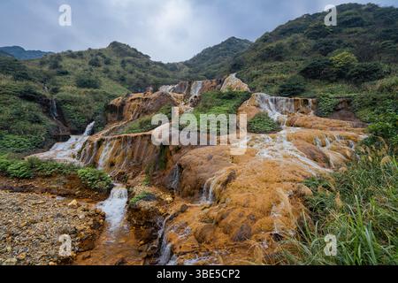 Image haute résolution des chutes d'or dans le nord de Taïwan, une cascade spectaculaire teintée par des eaux riches en minéraux qui coulent sur des rochers de couleur rouille Banque D'Images