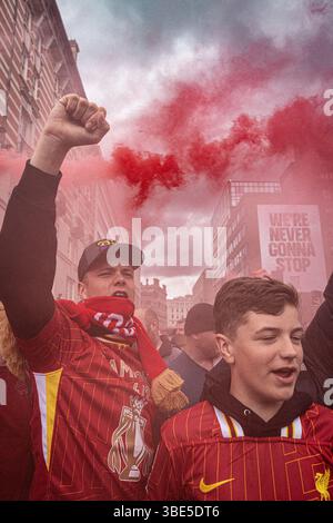 Les fans de Liverpool célèbrent avec des fusées rouges alors que les joueurs de football font le tour de la ville dans un bus à toit ouvert pendant le défilé de la victoire du Liverpool FC premier League. Banque D'Images