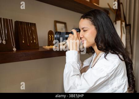 Un photographe prend des gros plans de bijoux exposés dans un magasin de sacs. L'accent est mis sur la capture des détails complexes des colliers élégants et de l'oreille Banque D'Images