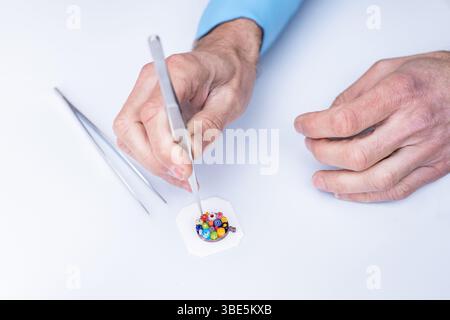 Un artisan qualifié fabrique des pièces complexes en verre de Burano et Murano avec des outils de précision. Placé sur un fond blanc, ce processus artistique met en valeur Banque D'Images