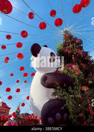 Décorations du nouvel an chinois vibrantes ornent les rues, avec des lanternes rouges vives et un grand panda gonflable, créant un atmo festif et joyeux Banque D'Images