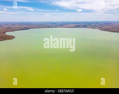 Photographie aérienne capturant un vaste lac verdoyant et calme entouré d'une vaste campagne plate dans le Victoria, en Australie. Le ciel bleu avec clou dispersé Banque D'Images