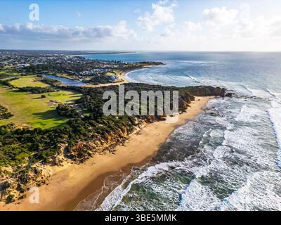 Vue aérienne d'un paysage côtier présentant une plage de sable, des vagues de l'océan et une végétation luxuriante dans la Great Ocean Road, Australie. Le rivage tranquille Banque D'Images
