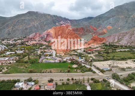 Vue aérienne de Purmamarca, Jujuy, Argentine, mettant en valeur ses collines multicolores vibrantes et son charmant village niché dans la vallée, sous un ciel nuageux Banque D'Images