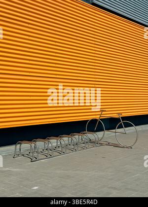 Une image frappante mettant en valeur un bâtiment industriel moderne avec un extérieur orange vif. Dispose d'un porte-vélos minimaliste conçu de manière créative dans le Banque D'Images