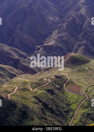 Vue aérienne d'une route sinueuse sertie à travers le terrain luxuriant et accidenté près du village de Tejeda sur l'île de Gran Canaria. La route met en valeur les plongeurs Banque D'Images